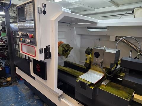 Torno CNC de base plana con guías box way amarillas, plato de tres garras naranja.