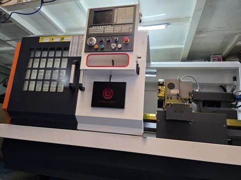 Plano cercano del torno CNC de base plana centrado en la consola CNC abatible, con el cabezal.