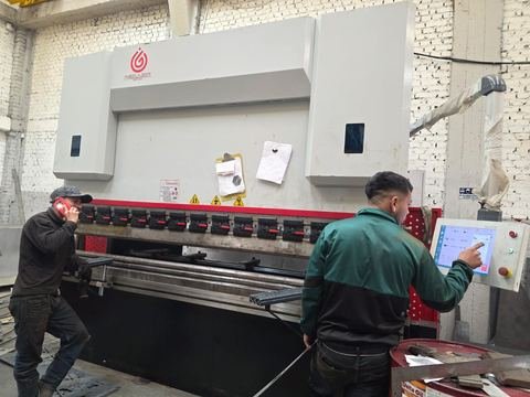 Plegadora CNC de pórtico en C con punzones segmentados y matriz en V en una nave de ladrillo.