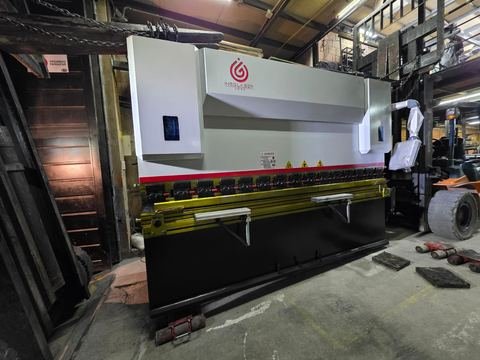 Plegadora CNC recién ubicada dentro de la bodega, vista 3/4 completa: pórtico en C, punzón segmentado montado.