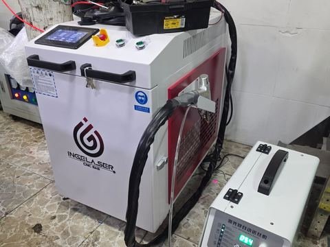 Soldadora láser de mano Ingelaser en el taller: carro blanco y rojo con pantalla táctil, seta de emergencia.