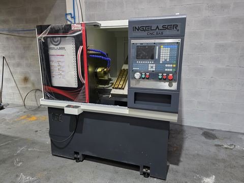 Torno CNC compacto con la puerta de la cabina abierta en taller de pared en bloque: plato de tres garras.