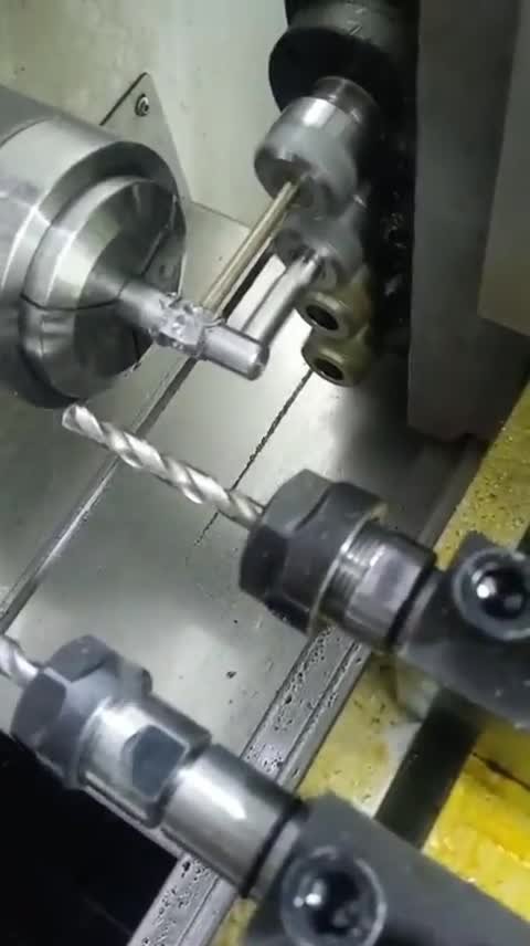 Interior de un torno CNC compacto: plano muy cerrado del husillo con pinza sujetando un eje pequeño mientras el carro acerca.